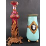 A Victorian cranberry glass tall perfume bottle, held in a gilt foliate stand, 30cm tall, and a pale