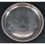 A Georgian circular silver drinks tray engraved and gadrooned, raised on three claw supports, 22cm