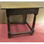 A small 18th century oak occasional table raised on four gun barrel supports, with single carved