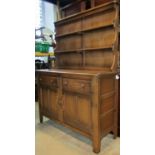 An Ercol stained elm cottage dresser, the base enclosed by a pair of twin panelled doors and two