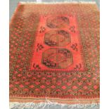 An Afghan Turkoman rug with large elephant foot design in varying orange, brown and blue/black