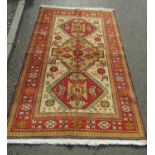 A Turkish Kazak rug with three central hooked medallions in neutral tones of ochre, vermillion and