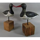A pair of carved wood red billed Oyster Catchers set on blocks of driftwood.
