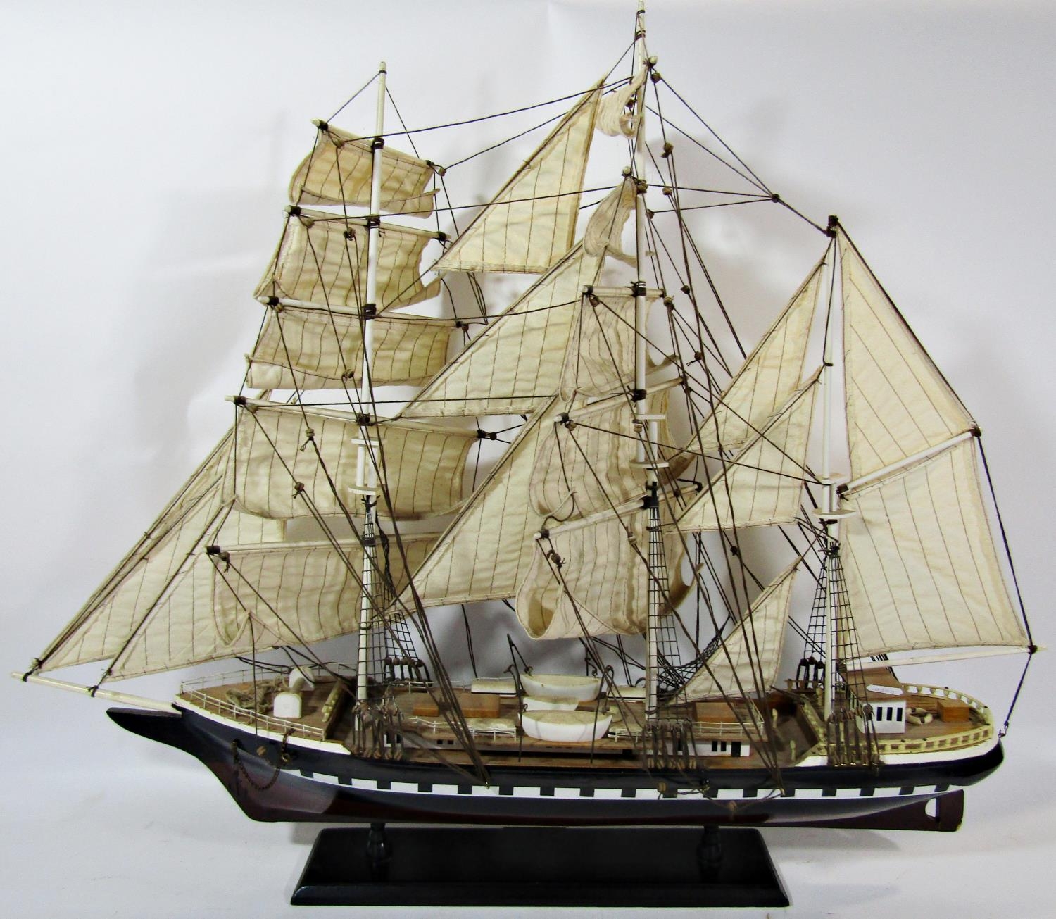 A wooden model of a three masted sailing ship in full sail, on a wooden stand, 79cm long x 67cm high