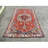 A Central Persian Bakhtiar rug with an elongated floral medallion amongst flowers on a madder pink