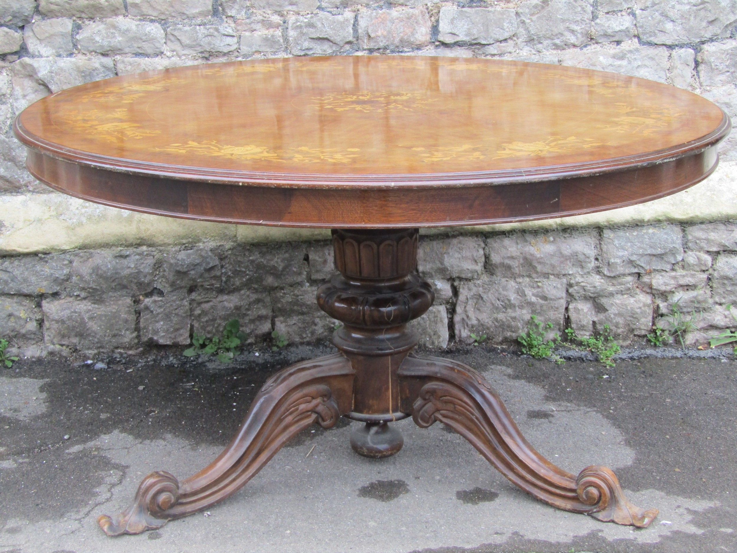 A Victorian style circular breakfast table with inlaid floral marquetry detail raised on a squat