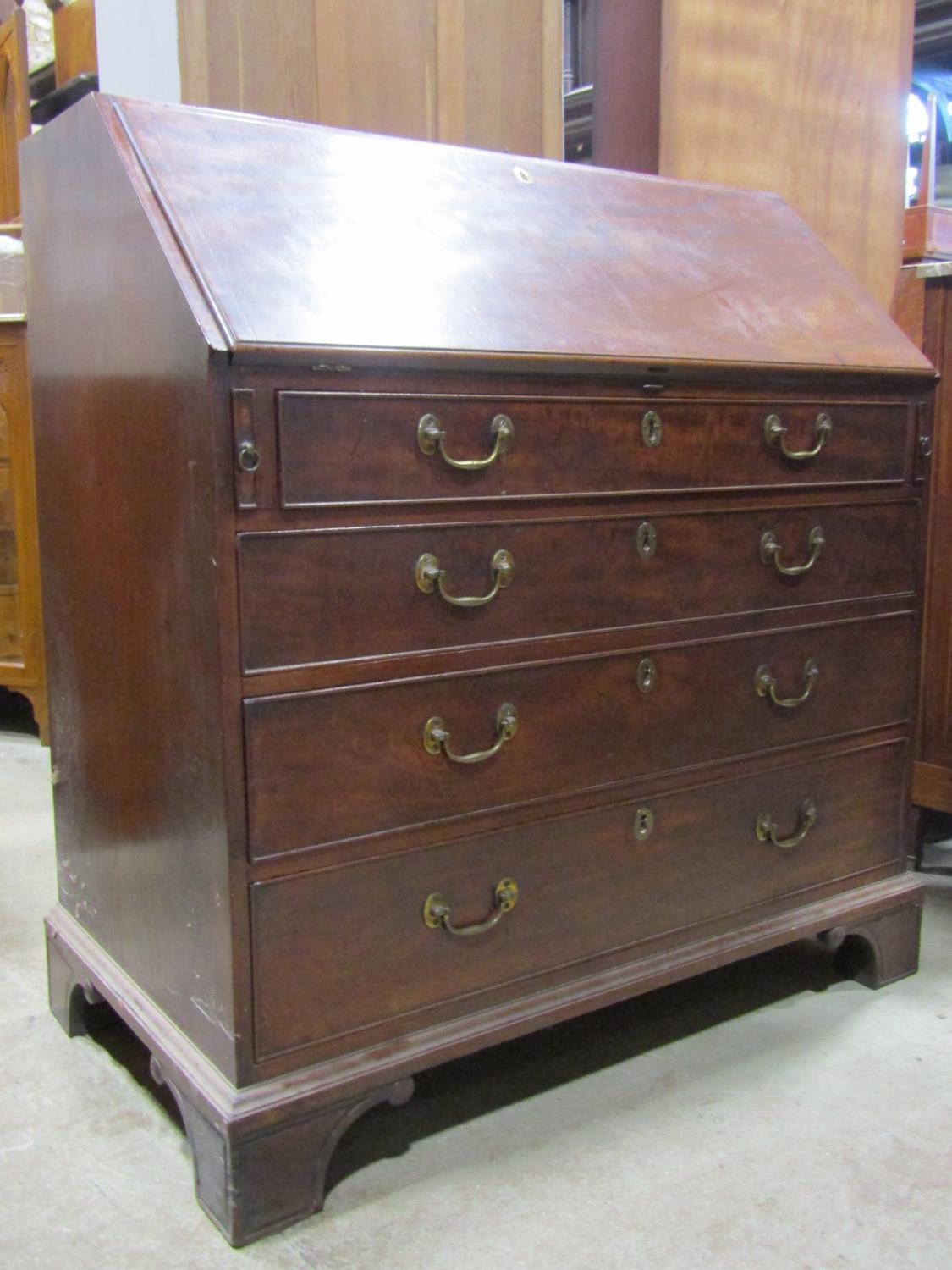 A Georgian mahogany bureau, the fall flap enclosing a fitted interior of small drawers, pigeon holes