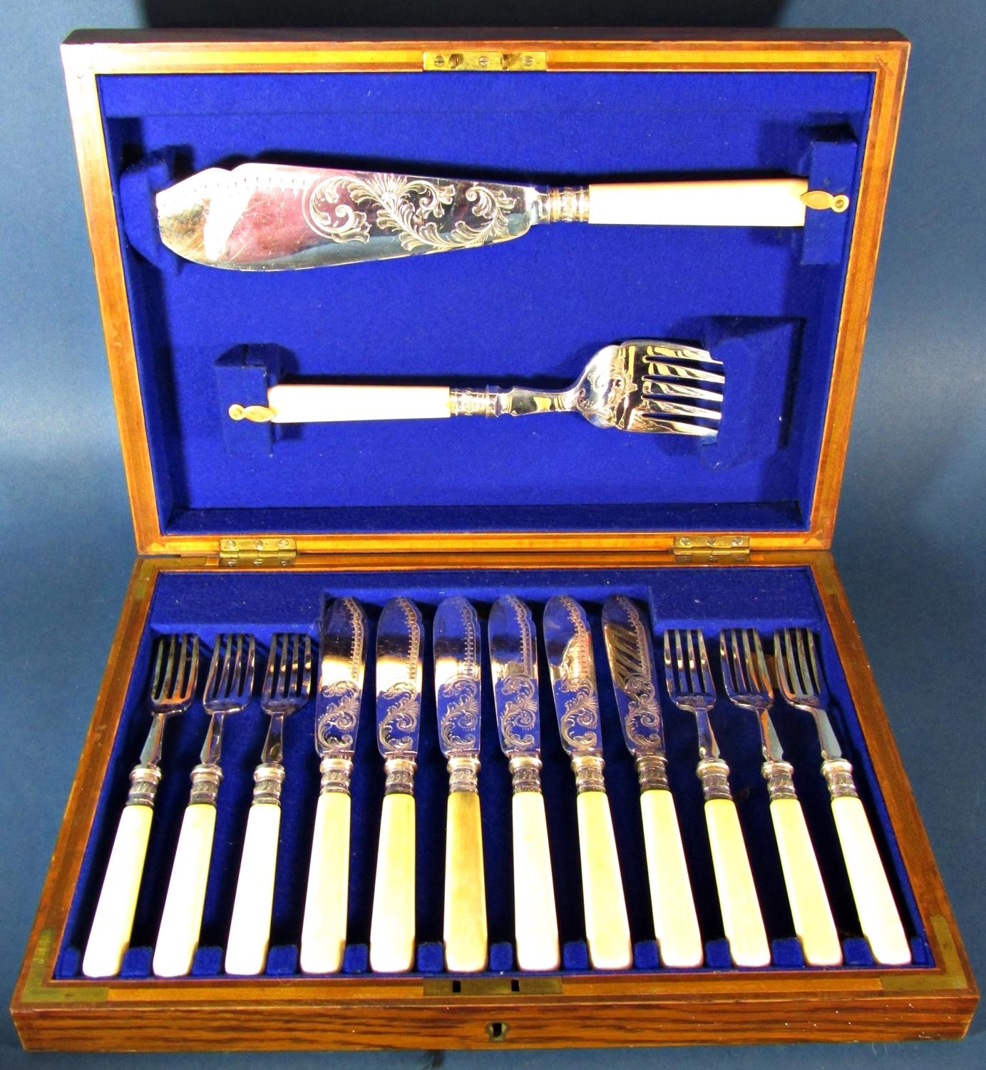 An antique oak canteen of silver plated fish knives and forks for six settings complete with serving