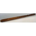 A carved wooden club like instrument with foliate carving to the club, 63cm long