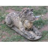 A weathered cast composition stone garden in the form of a recumbent lion with flowing mane, 38 cm