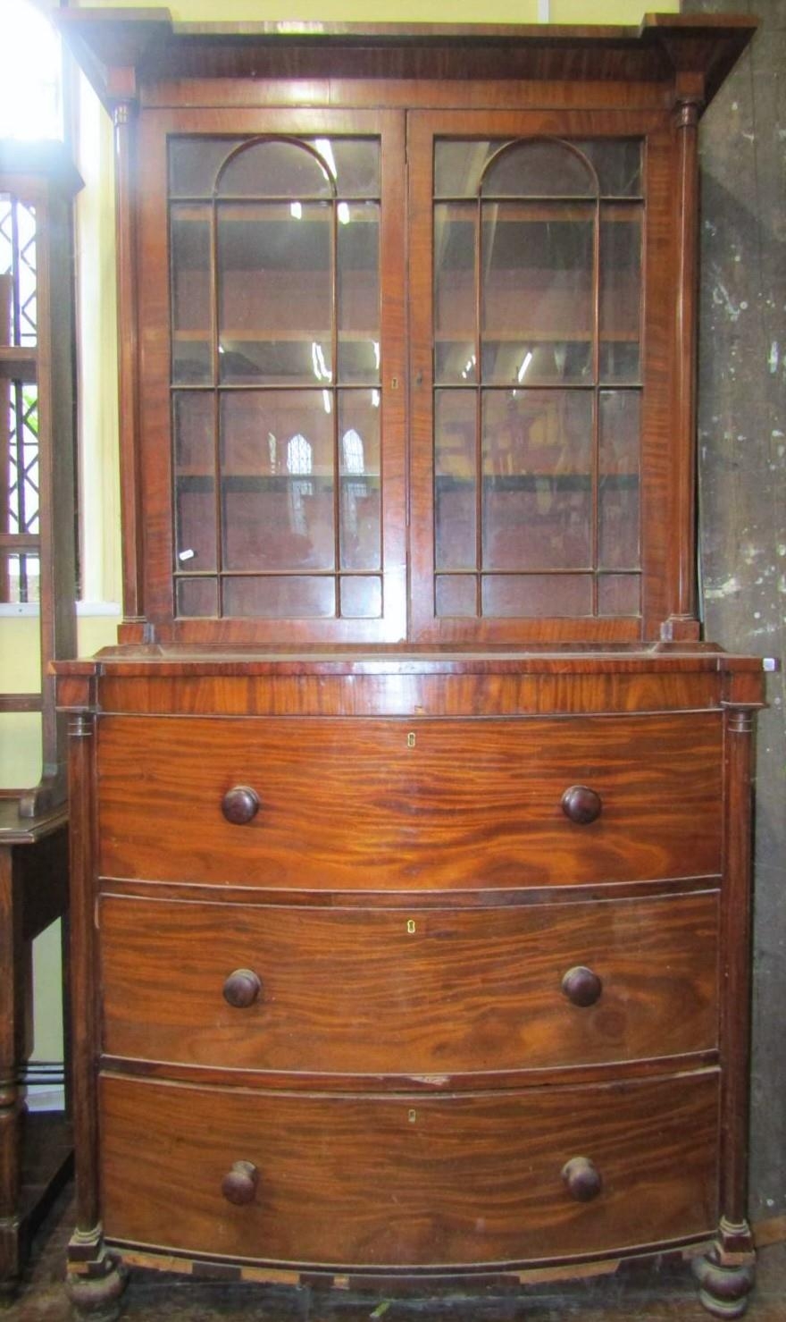 A regency mahogany secretaire bookcase, the base of bow fronted outline fitted with two deep