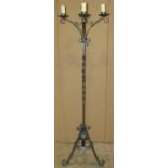 A heavy iron work lamp standard with four scrolling branches and raised on scrolled tripod