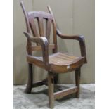 A vintage rustic wooden open armchair with dished seat