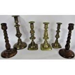 A collection of candlesticks with nine brass examples, two copper examples and a pair of wooden