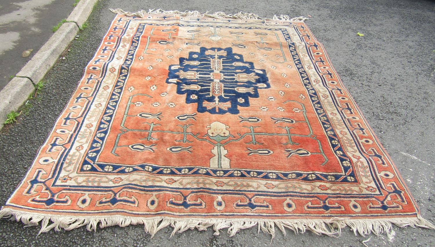 A large Turkish carpet with a central stepped medallion and stylised flowers on a pink ground, 237cm