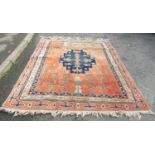 A large Turkish carpet with a central stepped medallion and stylised flowers on a pink ground, 237cm