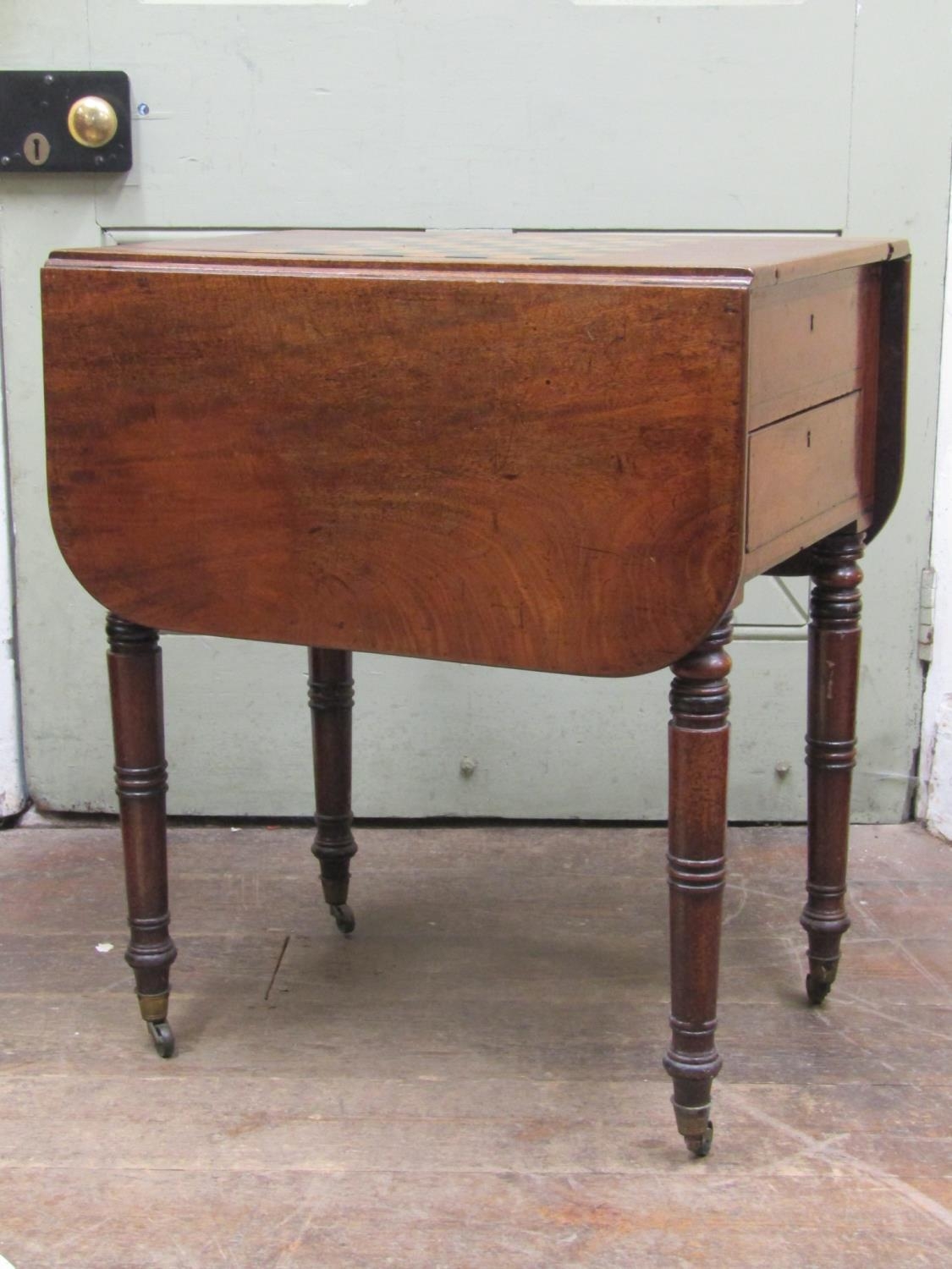 A 19th century mahogany drop leaf games table, the sliding and convertible top enclosing a chequer