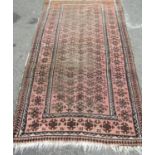 A worn Middle Eastern rug with repeated geometric design throughout in pale maroon and brown