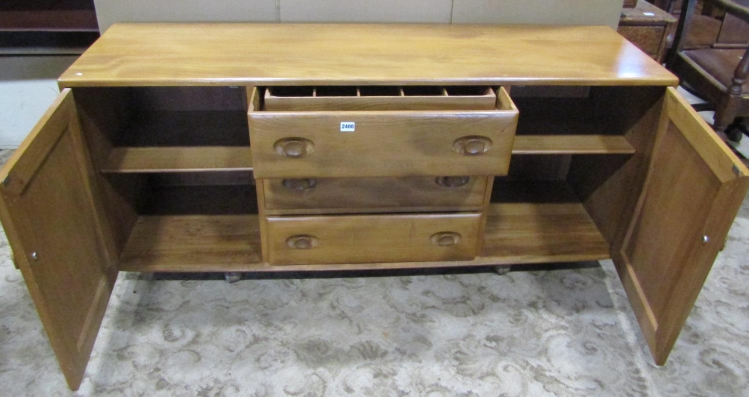 An Ercol light elm low sideboard enclosed by two doors flanking three drawers with oval dished - Image 2 of 3