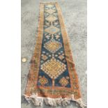 A North West Persian runner with a central row of interlocking medallions on a dark blur ground,