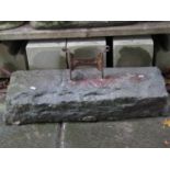 A wrought iron boot scraper set in a rectangular stone block 84 cm long x 30 cm wide