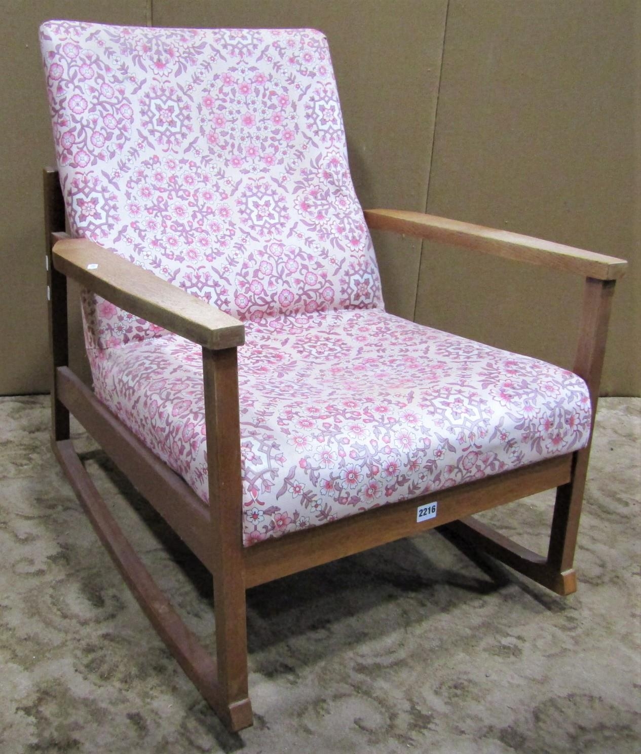 A vintage mid 20th century low oak framed rocking chair with combined upholstered seat and back