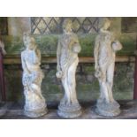 Three weathered cast composition stone garden ornaments in the form of maidens in varying pose,