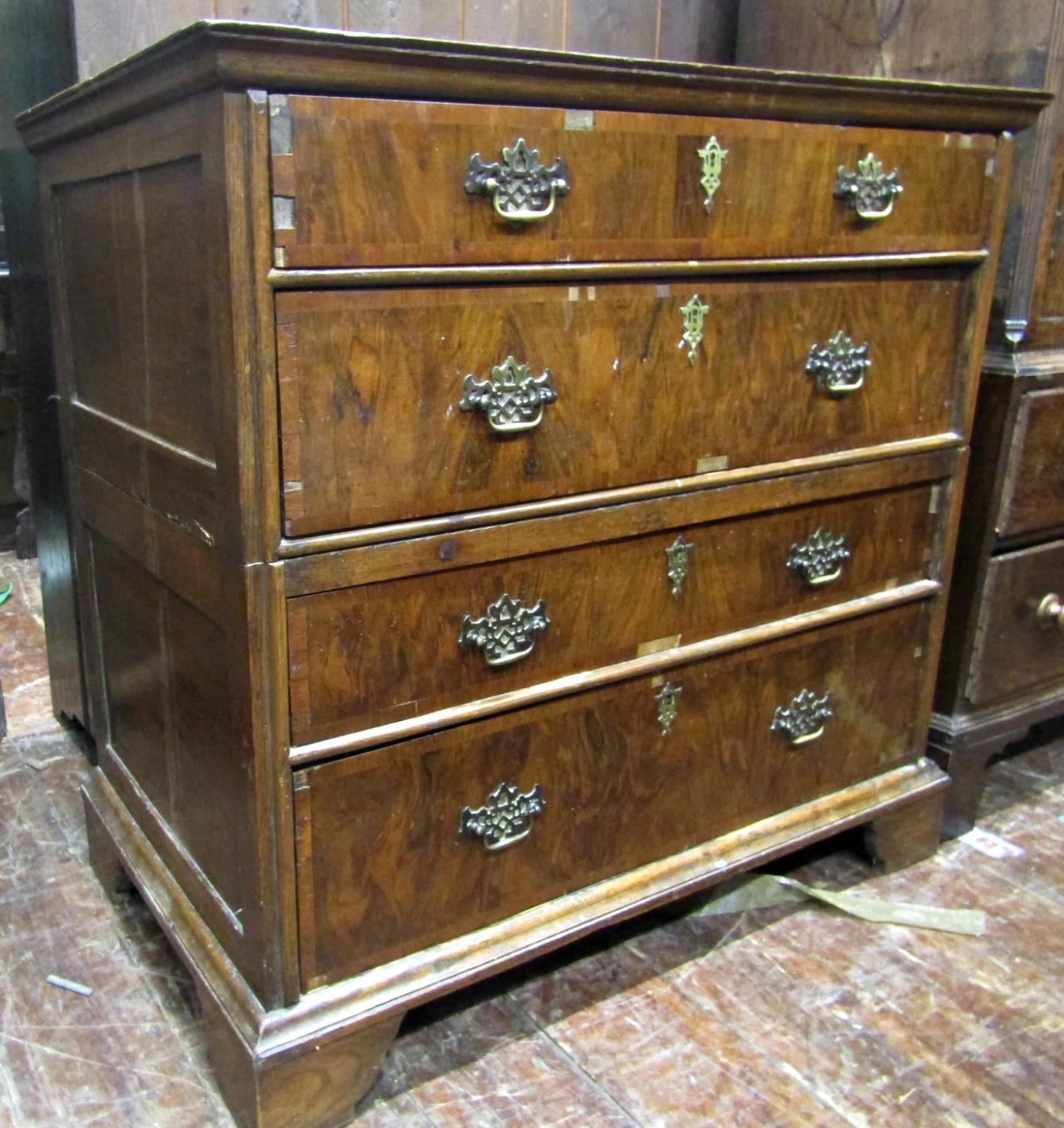 An antique countrymade chest of four long drawers, the carcass in two sections with figured walnut