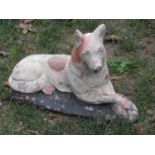 A cast composition stone garden ornament in the form of a recumbent dog with painted finish, 33 cm