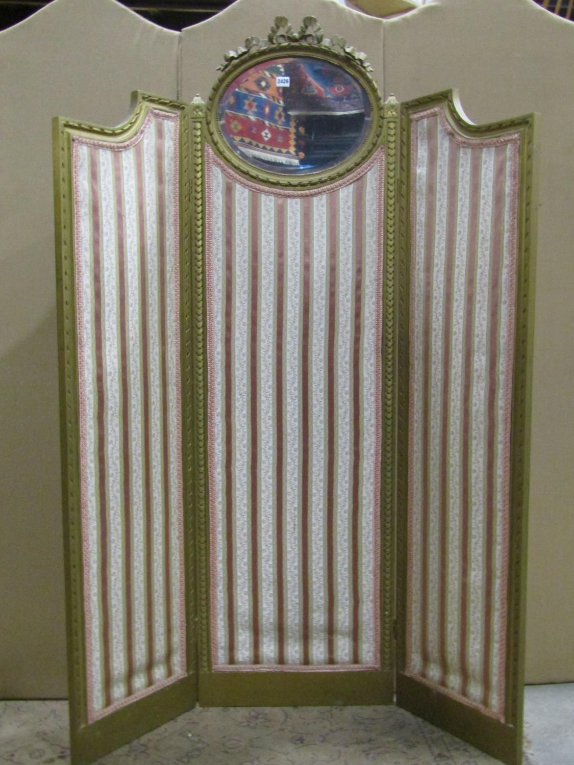 A floorstanding three fold gilt framed salon screen with moulded outline, the central panel