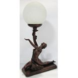 An Art Deco style bronze effect table lamp of a posing dancing girl holding aloft a globular lamp,