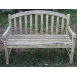 A weathered botanic teak garden bench with slatted seat and back beneath an arched rail, 4ft wide,