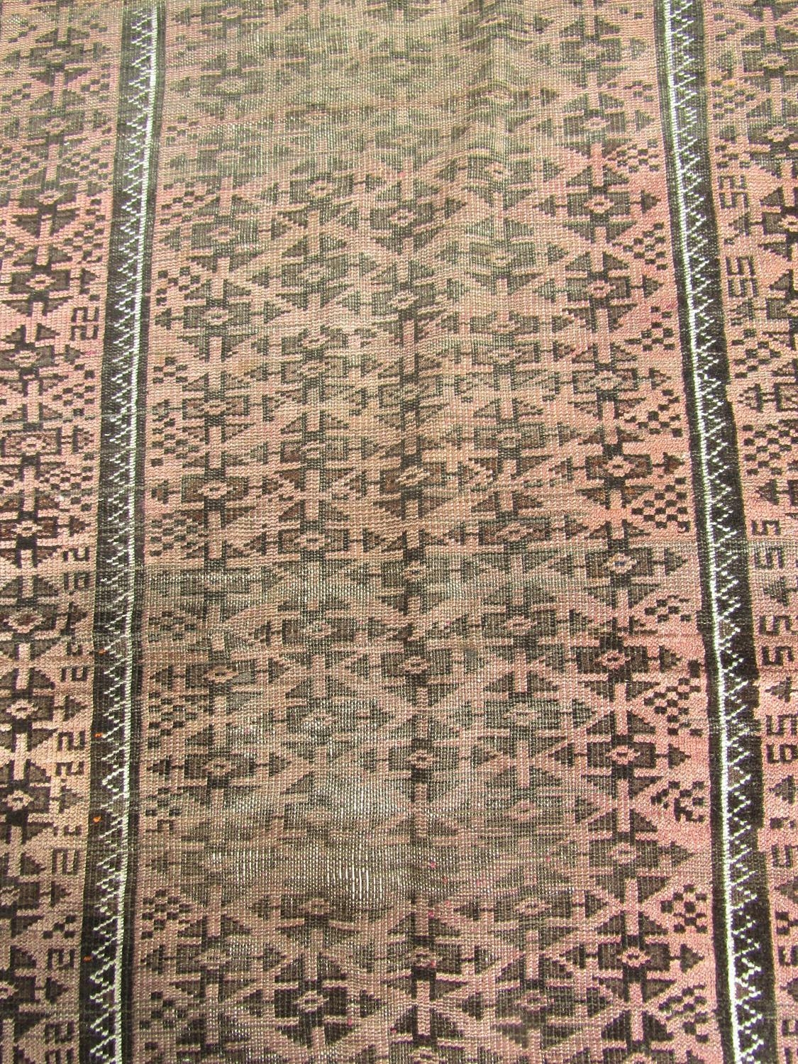 A worn Middle Eastern rug with repeated geometric design throughout in pale maroon and brown - Image 2 of 3