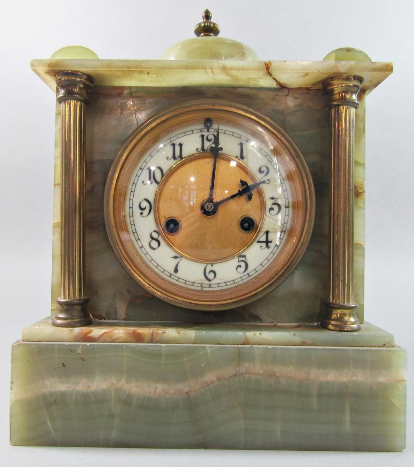 A late 19th century onyx mantel clock of classical form with brass supports enclosing an eight day