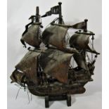 A vintage wooden model of a 16th century galleon in full sail, raised on a wooden stand, 36cm x 50cm