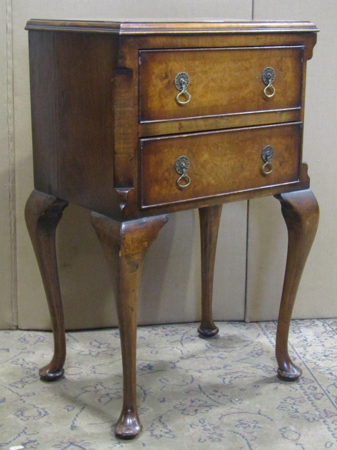 A small reproduction Queen Anne style walnut veneered oak lined two drawer chest raised on