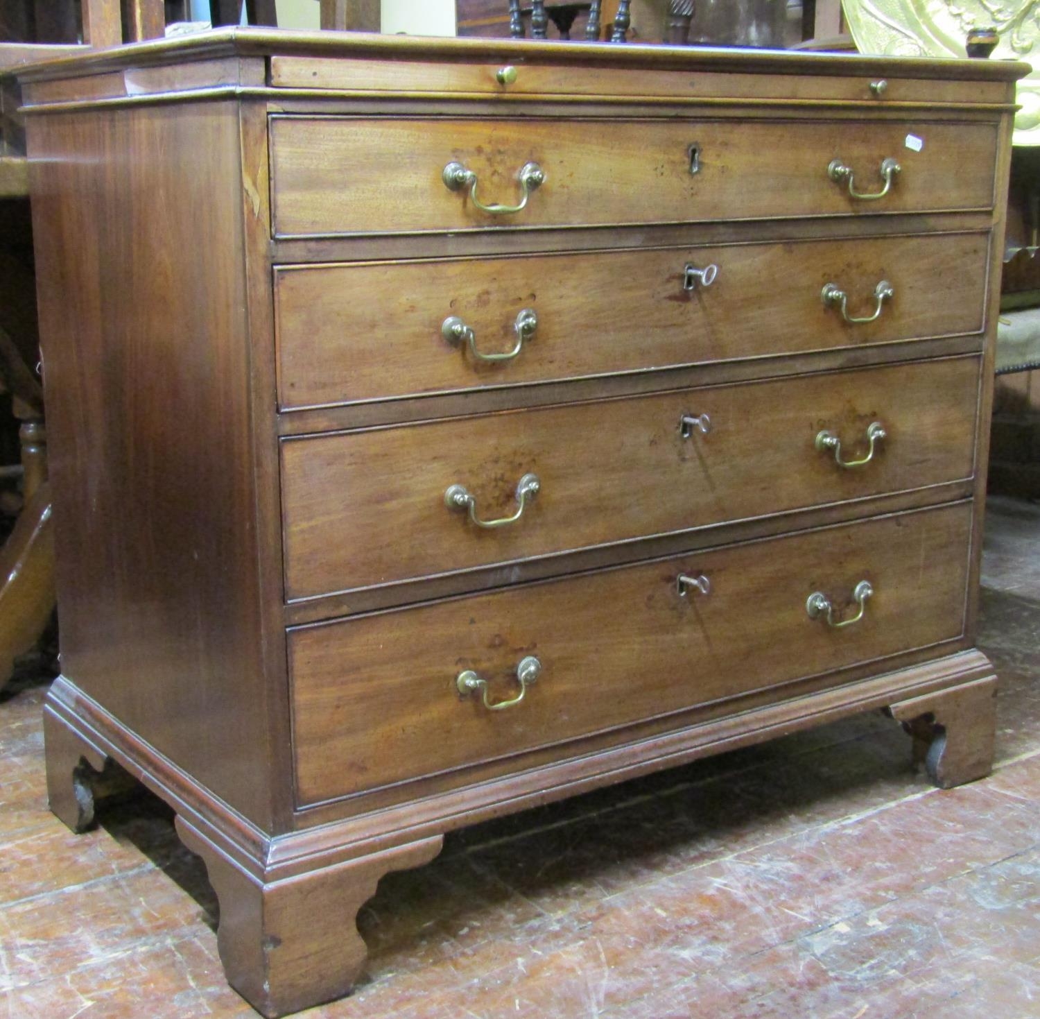 A Georgian mahogany and oak lined chest of four long graduated drawers enclosing a brush slide,