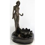 A bronze statue in the Art Nouveau style of a woman holding a flower beside a large lily pad, signed