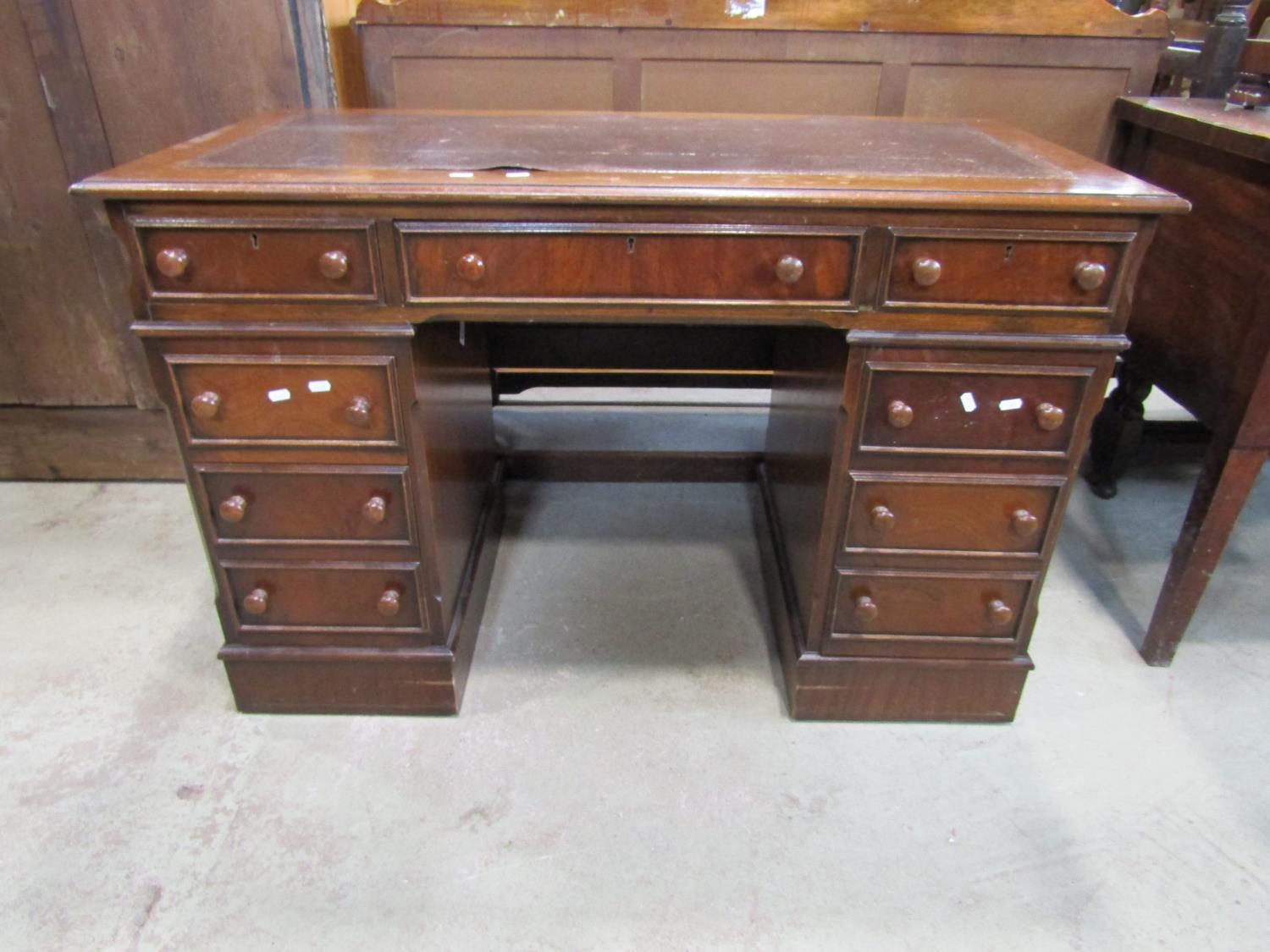 A reproduction mahogany kneehole twin pedestal writing desk, with inset leather panel top set over