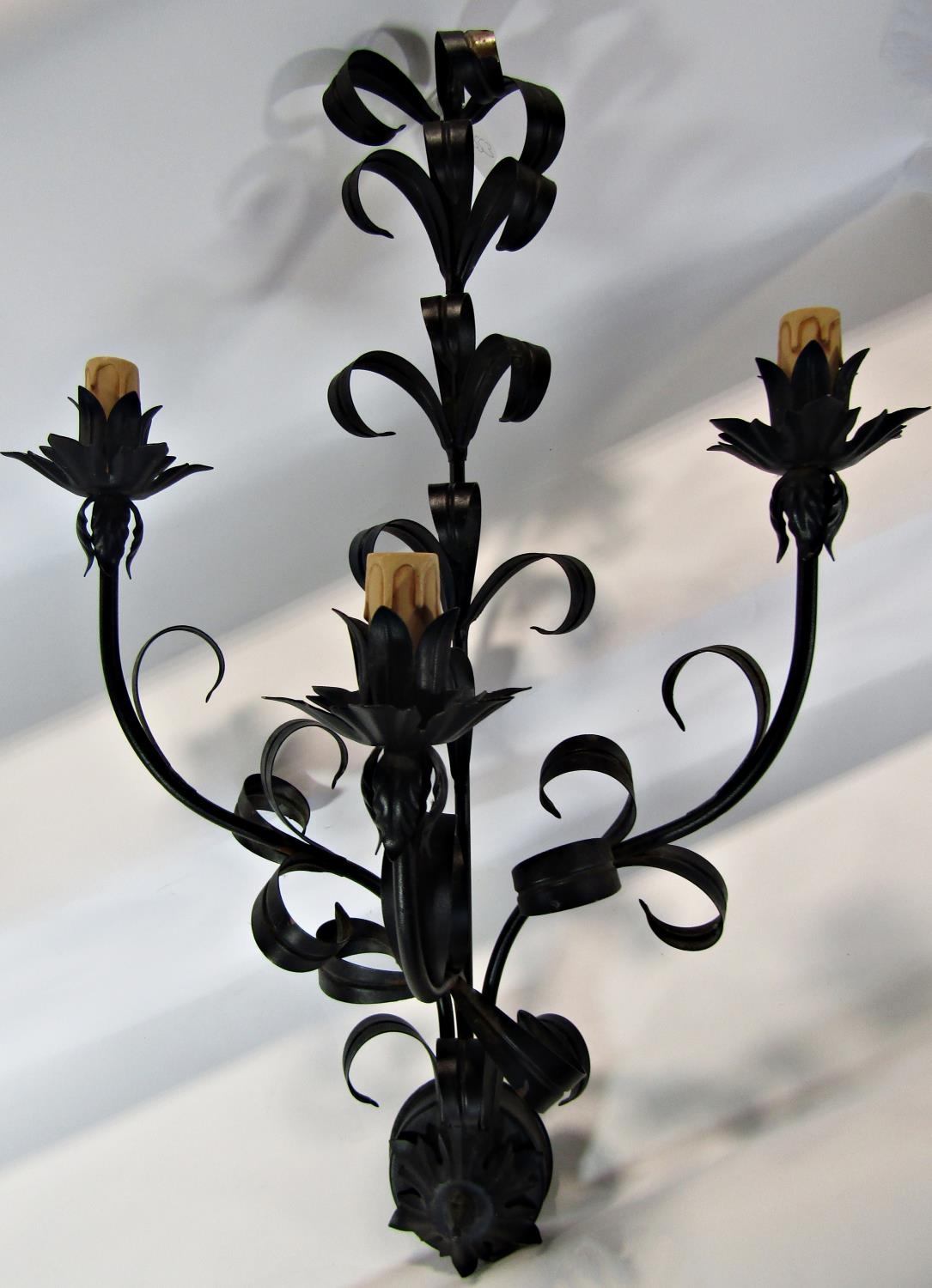 A pair of scrolled wrought iron wall sconces with three branches and foliate detail, 76 cm long
