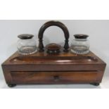 A 19th century rosewood inkstand with a central handle flanked by original inkwells with a single