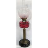 A J & S Lee & Sons Hinks patent oil lamp with a cranberry glass reservoir supported by a brass