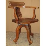 A Victorian walnut swivel office desk chair with pierced splat over a saddle shaped seat