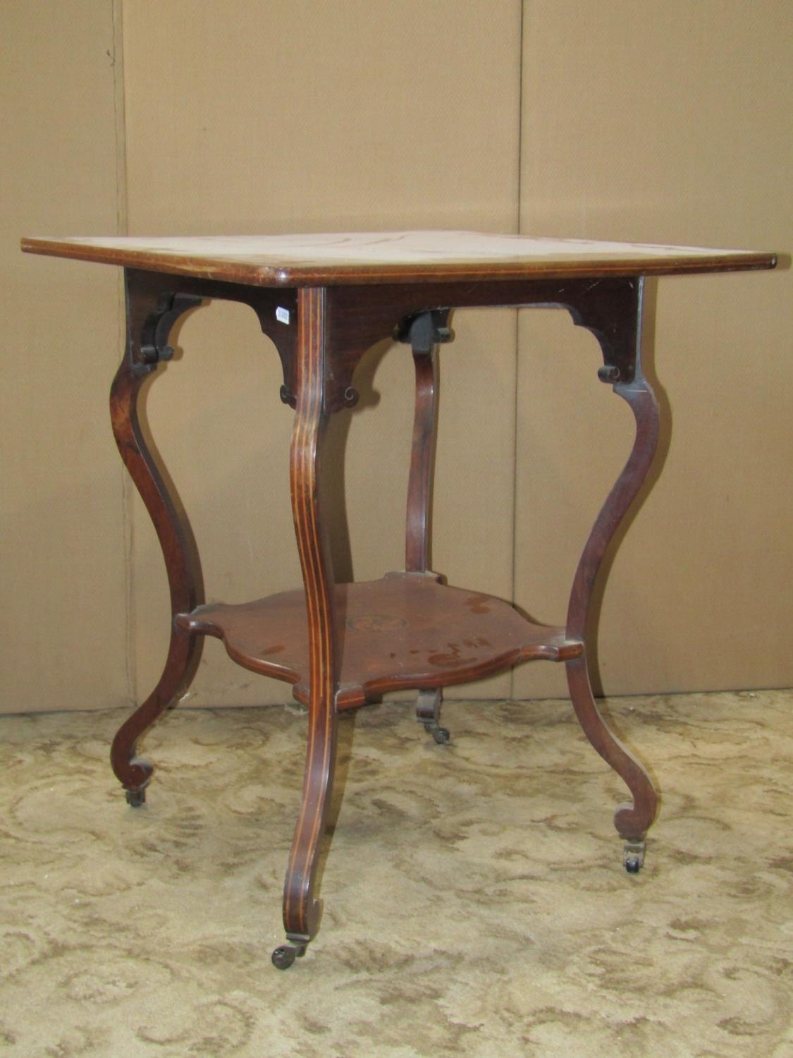 An inlaid Edwardian rosewood two tier occasional table raised on scrolled supports and castors,