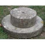 Two weathered carved natural stone mill stones of varying size, the largest 60 cm diameter x 10 cm