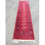 A Turkoman runner with a central row of elephant foot medallions on a red ground, 104cm x 69cm