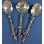 A pair of silver metal apostle style spoons bearing no hallmarks, together with a third similar