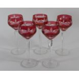 Five ruby cased wine glasses on a facetted stems and circular foot, 20cm tall.