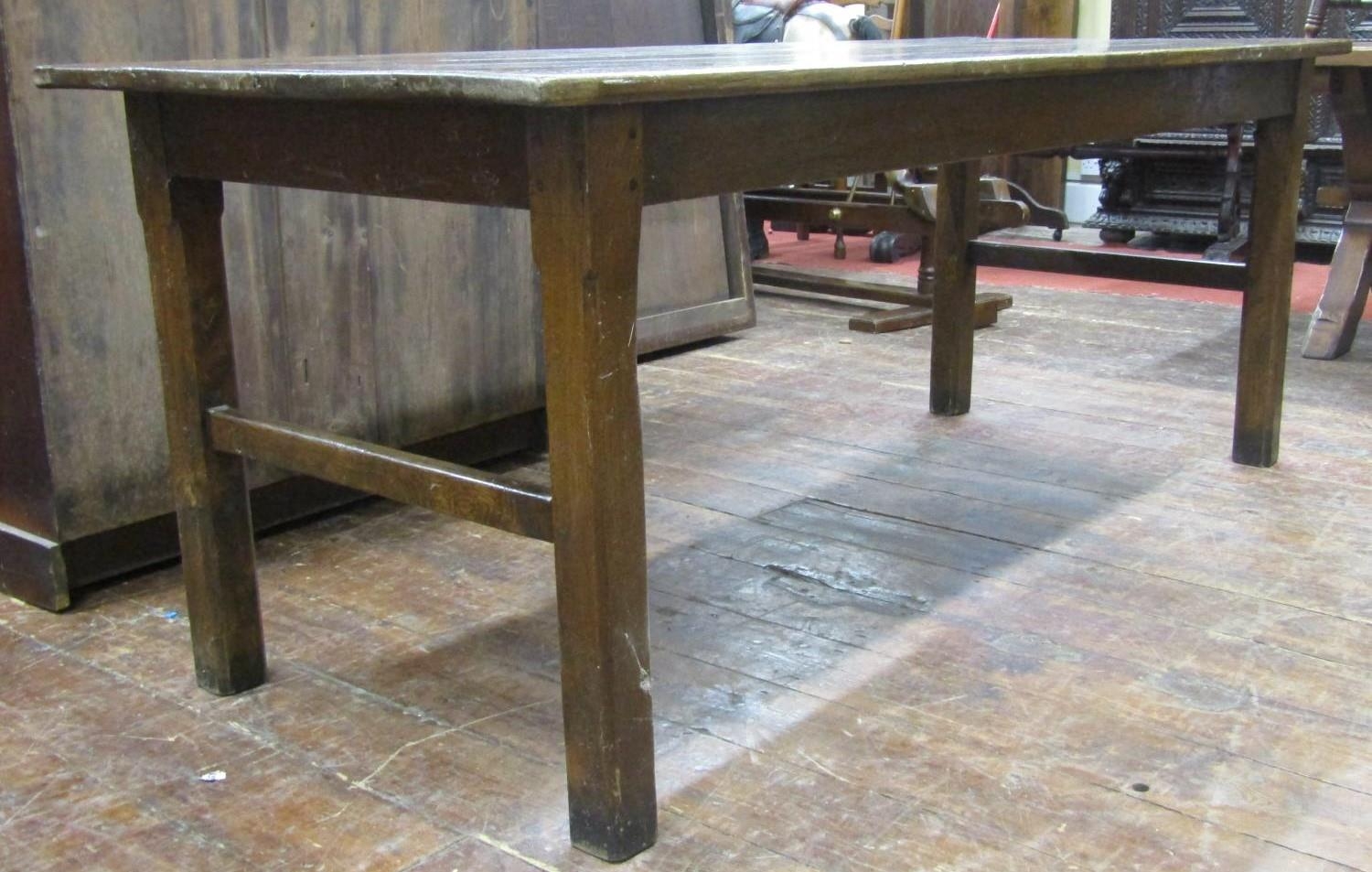 A Georgian oak farmhouse kitchen table, the plank top raised on chaffered supports, united by end