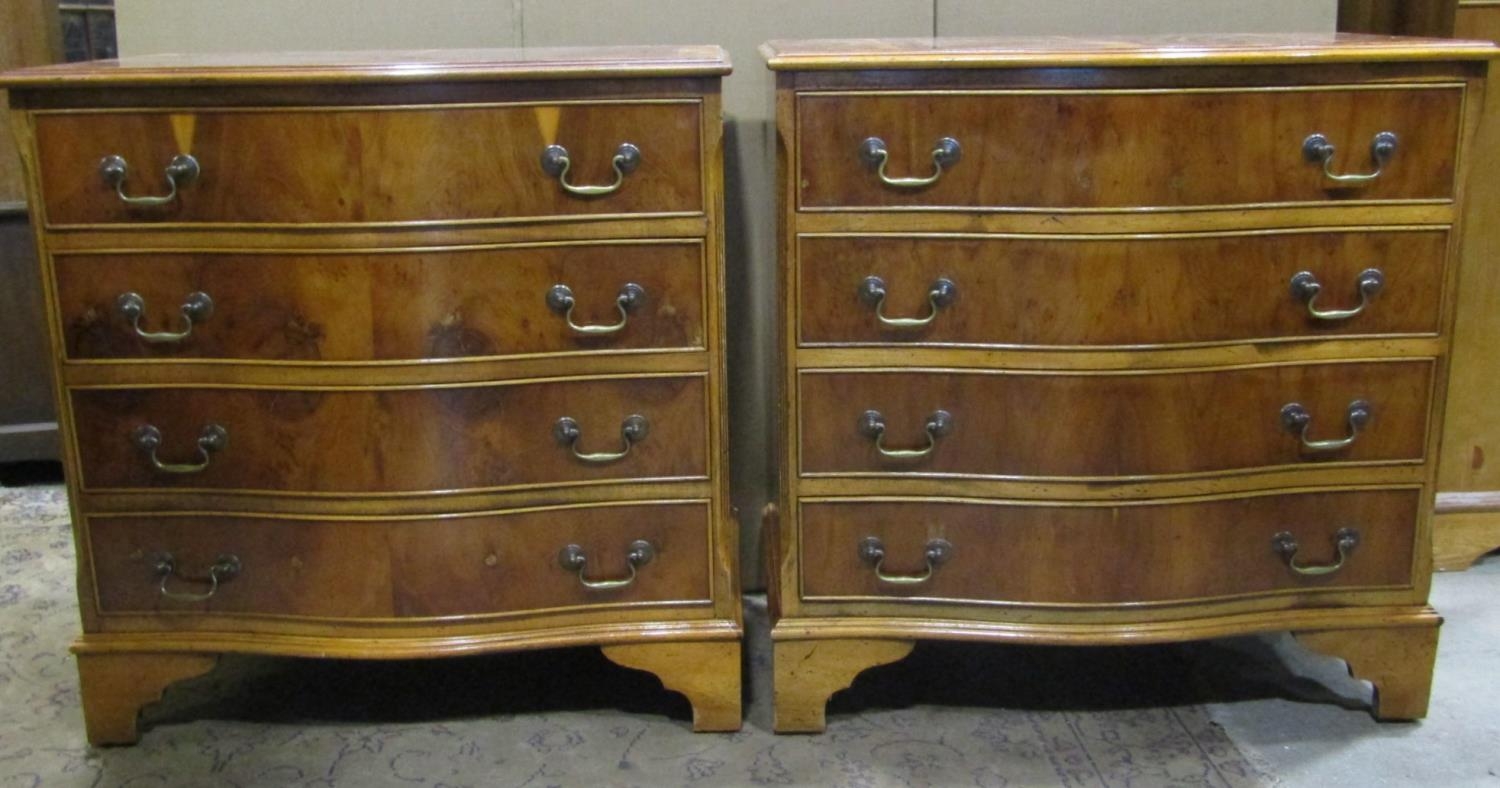 A pair of reproduction Georgian style yew wood veneered four drawer serpentine front chests of